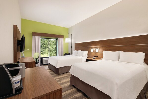 Habitación de hotel con dos camas, un escritorio, una silla, un televisor y una ventana con cortinas.