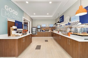A breakfast area with a counter, a refrigerator, and a display of breakfast items.