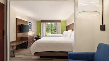 A hotel room with a bed, a desk, a chair, a television, and a window with curtains.