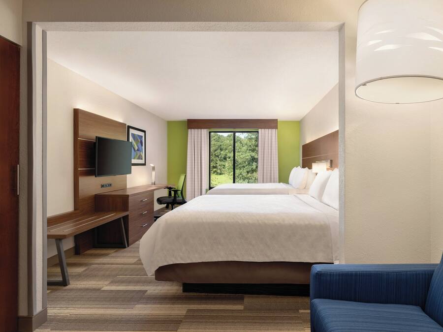 A hotel room with a bed, a desk, a chair, a television, and a window with curtains.