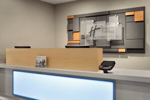 A hotel reception desk with a digital display, a cash register, and a sign for Holiday Inn Express & Suites. - Holiday Inn Express Hotel & Suites Lavonia by IHG (Lavonia)