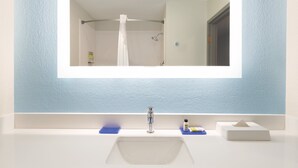 Un baño con un espejo grande, un lavabo y una ducha.