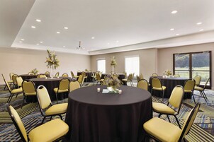 A conference room with round tables, yellow chairs, and floral centerpieces.