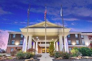 A hotel entrance with a flagpole, a flag, and a well-lit entrance. - Holiday Inn Express Vincennes by IHG (Vincennes)
