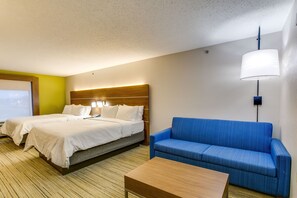 A hotel room with two beds, a blue sofa, and a wooden coffee table.
