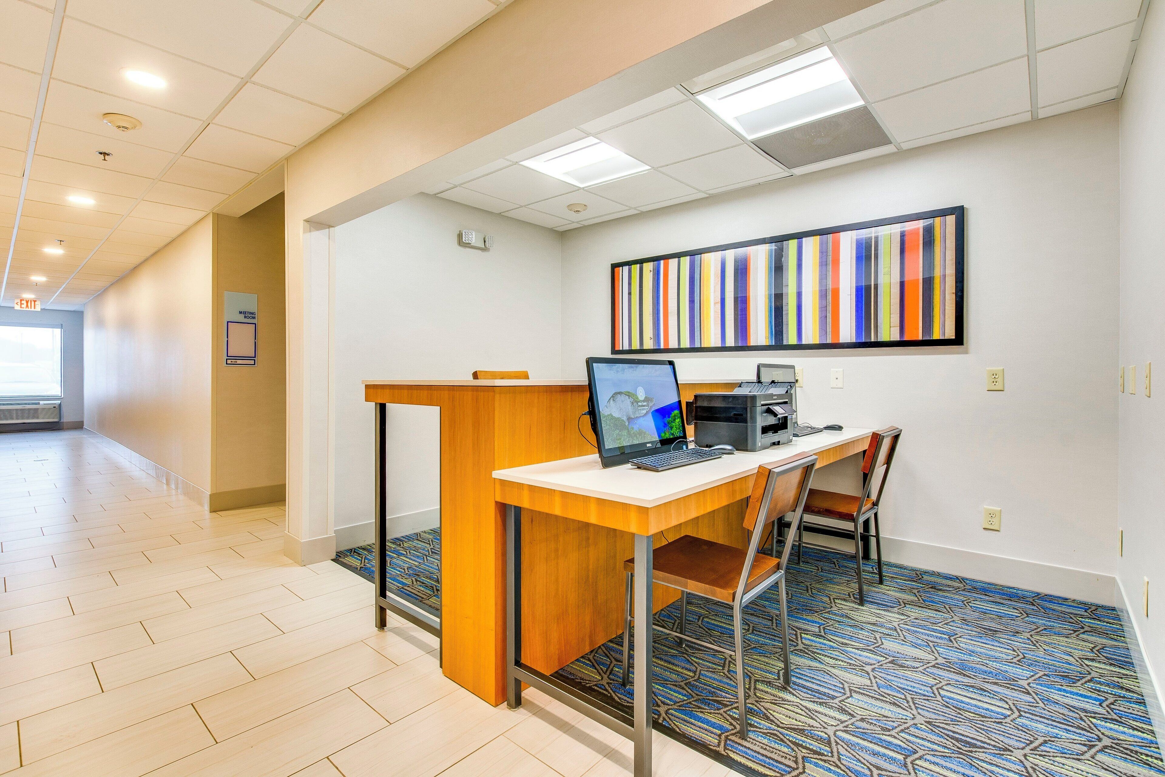 A modern office space with a desk, computer, and a colorful abstract painting on the wall.