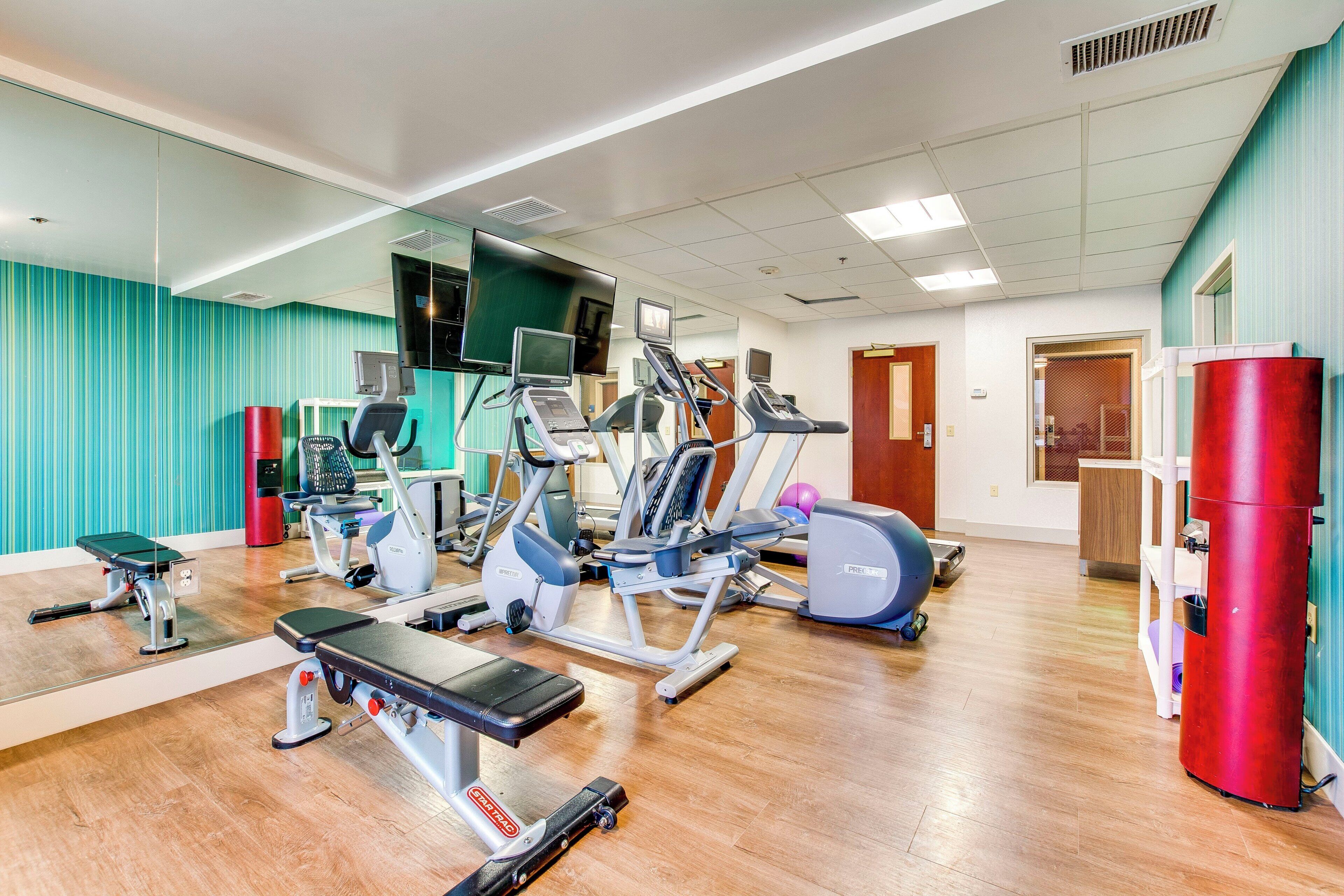A gym with various exercise equipment, including treadmills, stationary bikes, and weight machines.