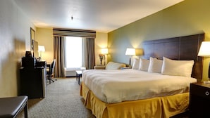 A hotel room with a large bed, bedside lamps, a desk with a computer, and a window with curtains. - GreenTree Inn & Suites Florence (Florence)