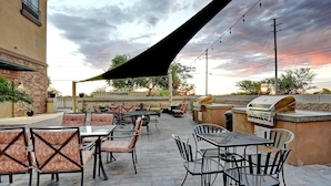 An outdoor patio with tables and chairs, a barbecue grill, and a large umbrella providing shade. - GreenTree Inn & Suites Florence (Florence)