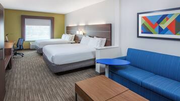 Una habitación de hotel con dos camas, un sofá azul, una mesita y un cuadro en la pared.