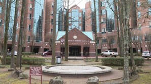 A building with a central entrance, surrounded by trees and a circular stone feature. - Holiday Inn Express & Suites Texarkana by IHG (Texarkana)