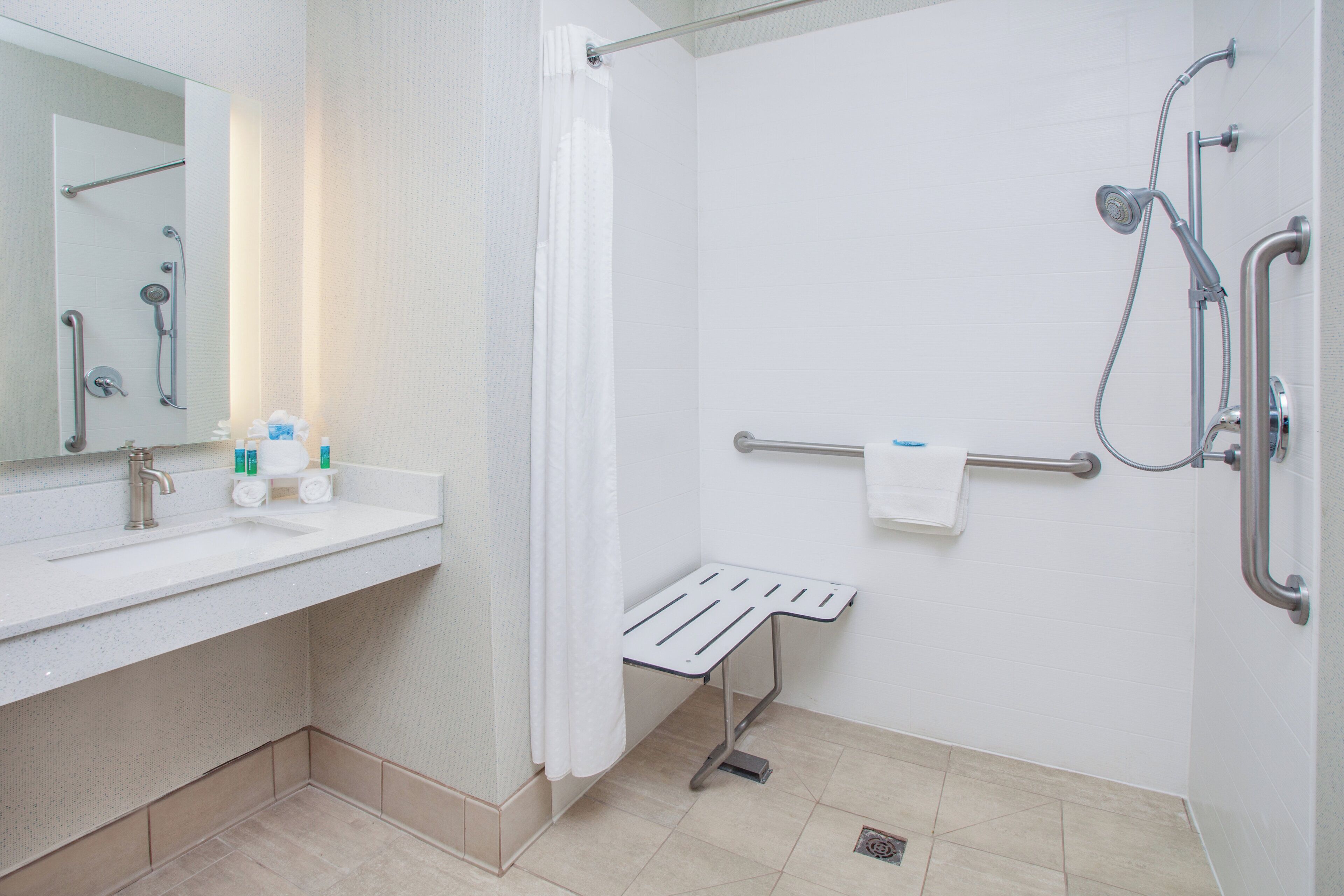 Un baño con ducha, lavamanos con espejo y toallero.