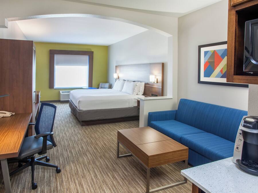 Een hotelkamer met een bed, een bureau, een stoel, een koffiezetapparaat en een televisie.