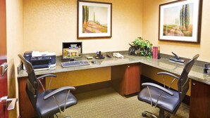 A hotel office with two black office chairs, a desk with a computer, printer, and phone, framed landscape paintings on the wall, and a potted plant. - Holiday Inn Express & Suites Texarkana by IHG (Texarkana)