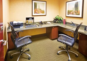 A hotel office with two black office chairs, a desk with a computer, printer, and phone, framed landscape paintings on the wall, and a potted plant. - Holiday Inn Express & Suites Texarkana by IHG (Texarkana)