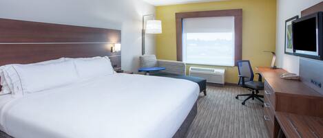 A hotel room with a large bed, a desk, a chair, a television, and a window with a view.
