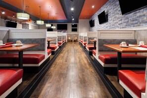 A restaurant interior with booths, wooden tables, and red cushioned seating.
