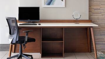 A modern office desk with a computer, keyboard, and chair.