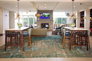 A spacious lobby with a fireplace, a television mounted on the wall, and a bar area with a variety of bottles.