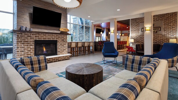 A modern living room with a fireplace, comfortable seating, and a bar area. - Holiday Inn Jackson Southeast - Pearl by IHG (Pearl)