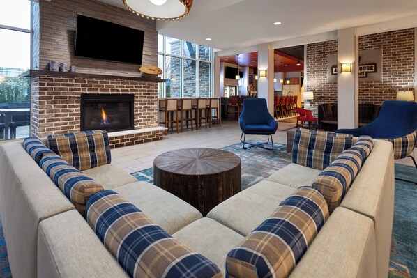 A modern living room with a fireplace, comfortable seating, and a bar area.