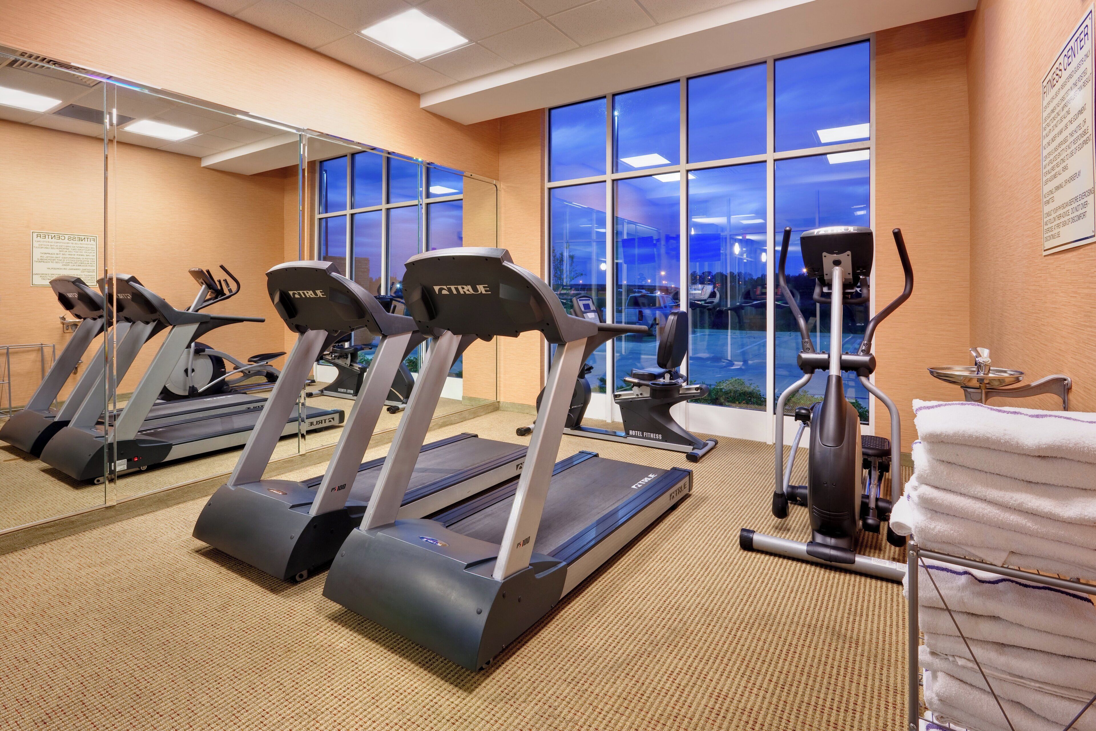 A fitness center with treadmills, an elliptical, and a mirrored wall.