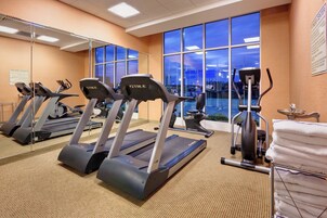 Un gimnasio con cintas de correr, elíptica y un espejo grande.