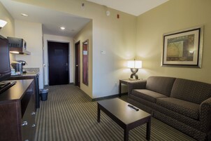 Habitación de hotel con kitchenette, sofá, mesa y lámpara.