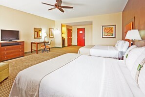 A hotel room with a large bed, a desk with a chair, a television, a ceiling fan, and a painting on the wall. - Holiday Inn Jackson Southeast - Pearl by IHG (Pearl)