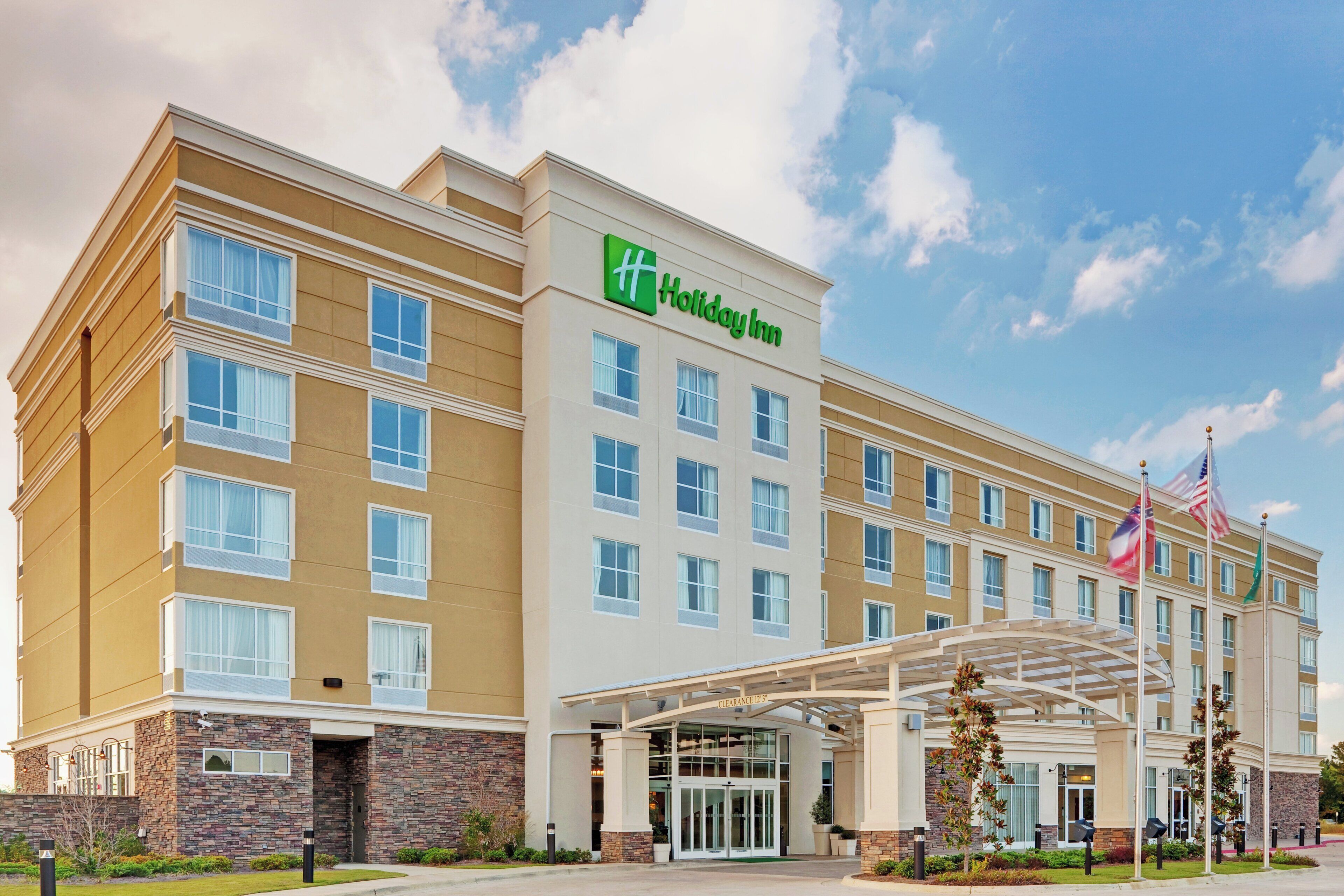 A Holiday Inn hotel with a modern facade, multiple windows, and a covered entrance.