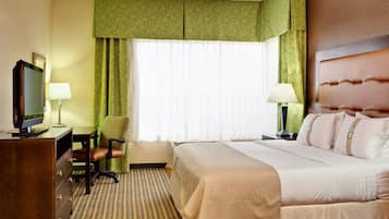 Habitación de hotel con cama, escritorio, computadora, silla y televisión.