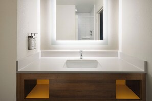 A bathroom with a white sink, a mirror, and wooden cabinets.