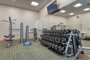 A gym with exercise equipment, a television screen, and an exit sign. - Holiday Inn Express & Suites Lincoln Airport by IHG (Lincoln)