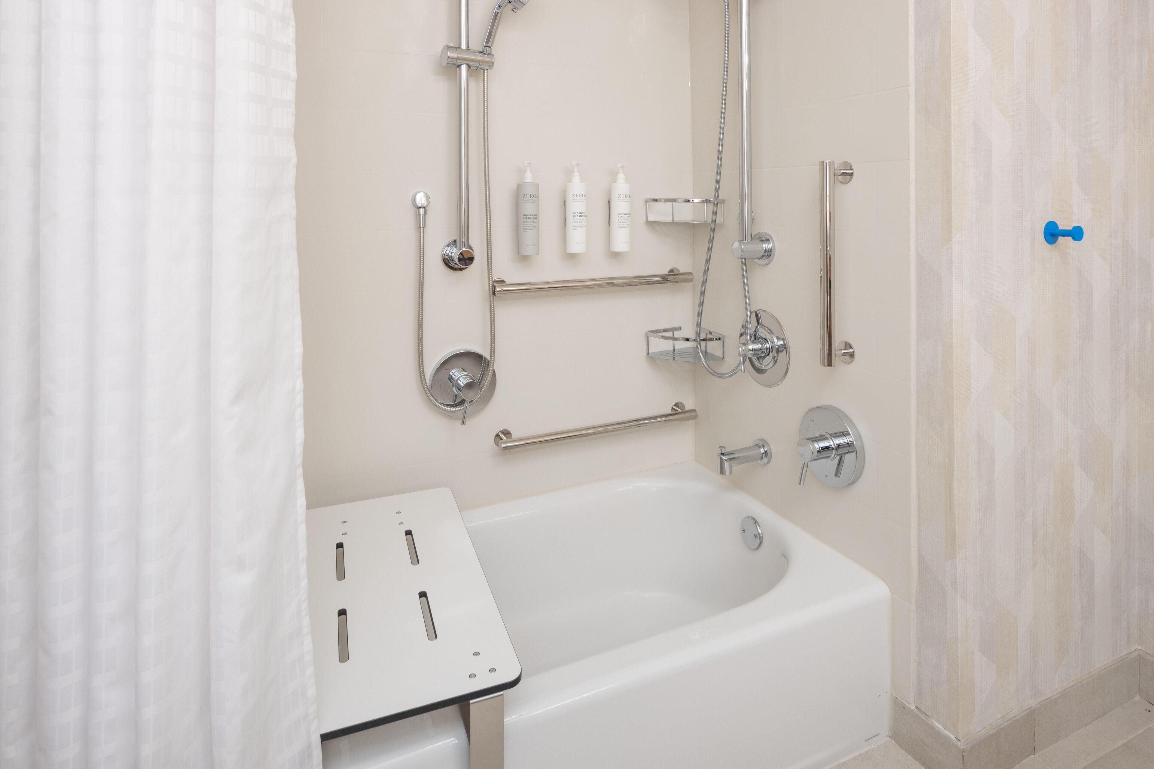 Un baño moderno con bañera, ducha y barras de apoyo.