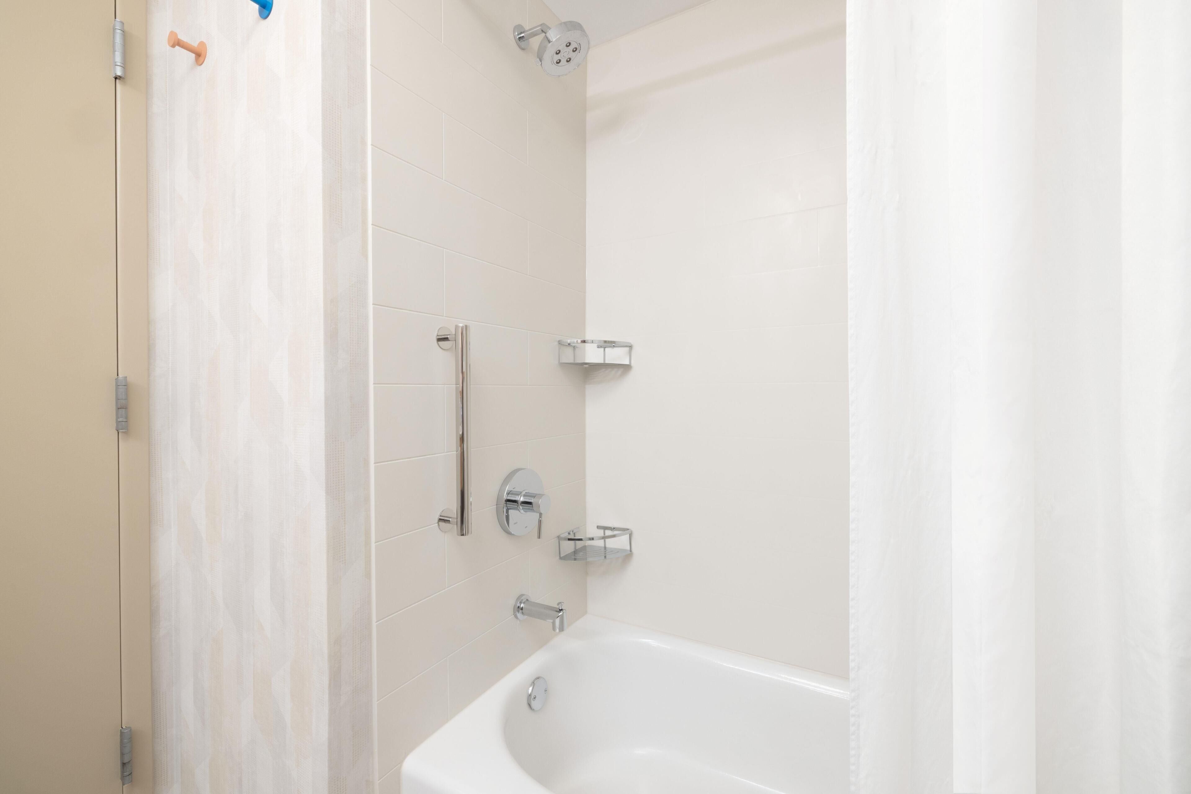 A bathroom with a bathtub, a showerhead, and a towel rack.
