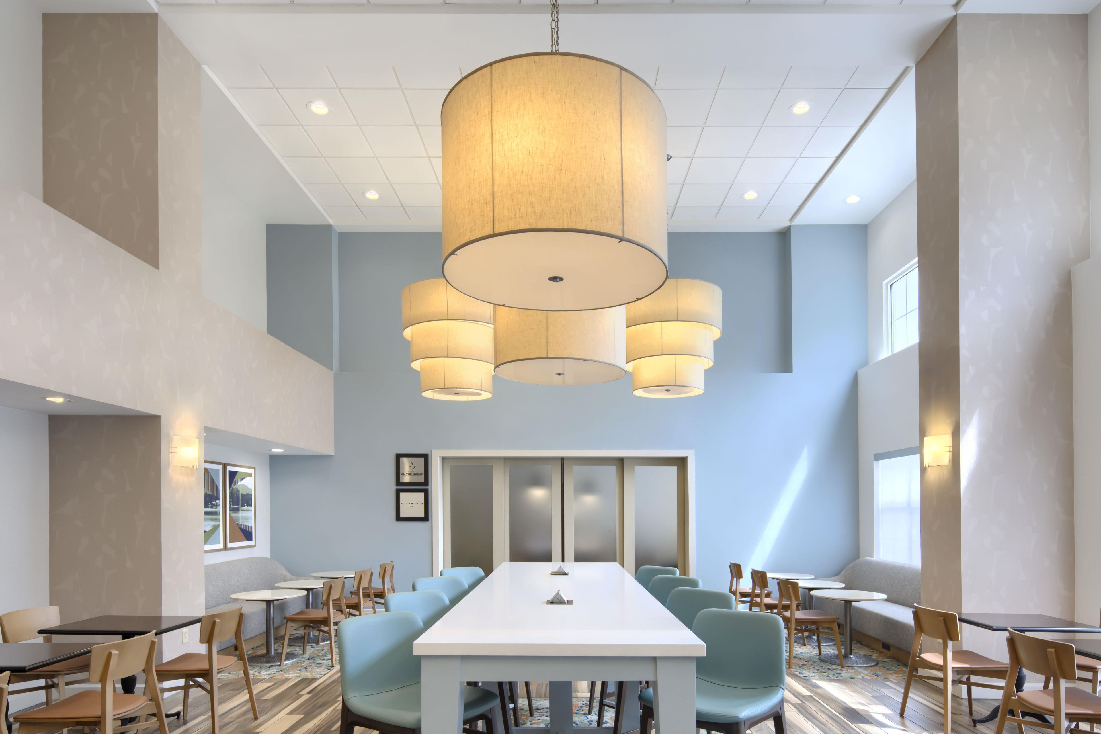 A conference room with a long table, chairs, and a large hanging light fixture.