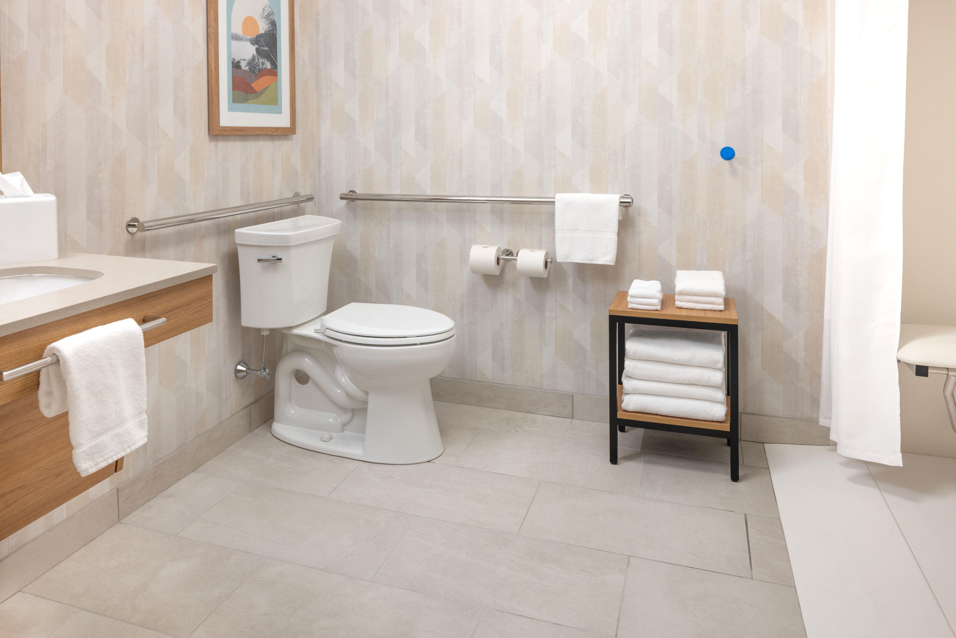 A modern bathroom with a toilet, bidet, vanity, and a shelf with towels.