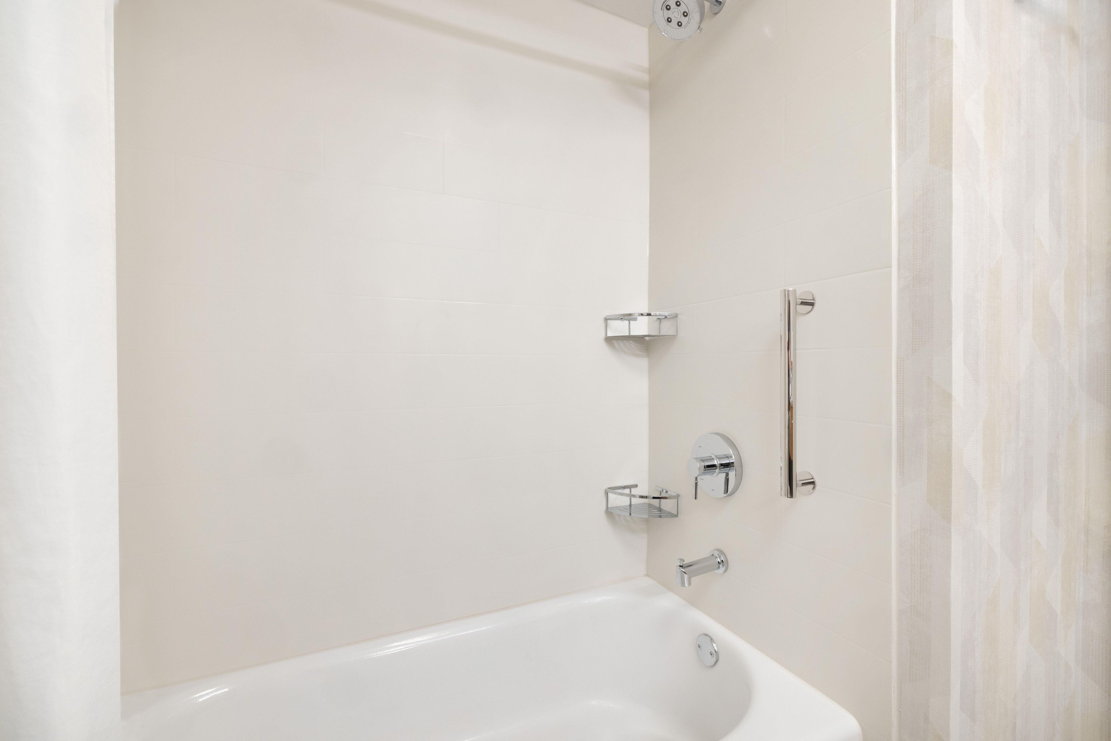 A modern bathroom with a white bathtub, a showerhead, and a towel rack.