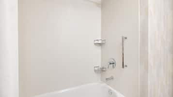 A modern bathroom with a white bathtub, a showerhead, and a towel rack.