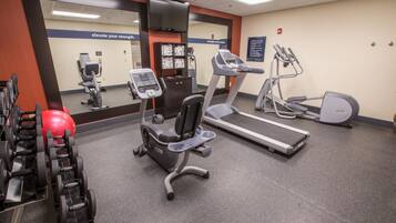 A gym with exercise equipment including treadmills, a stationary bike, and free weights.
