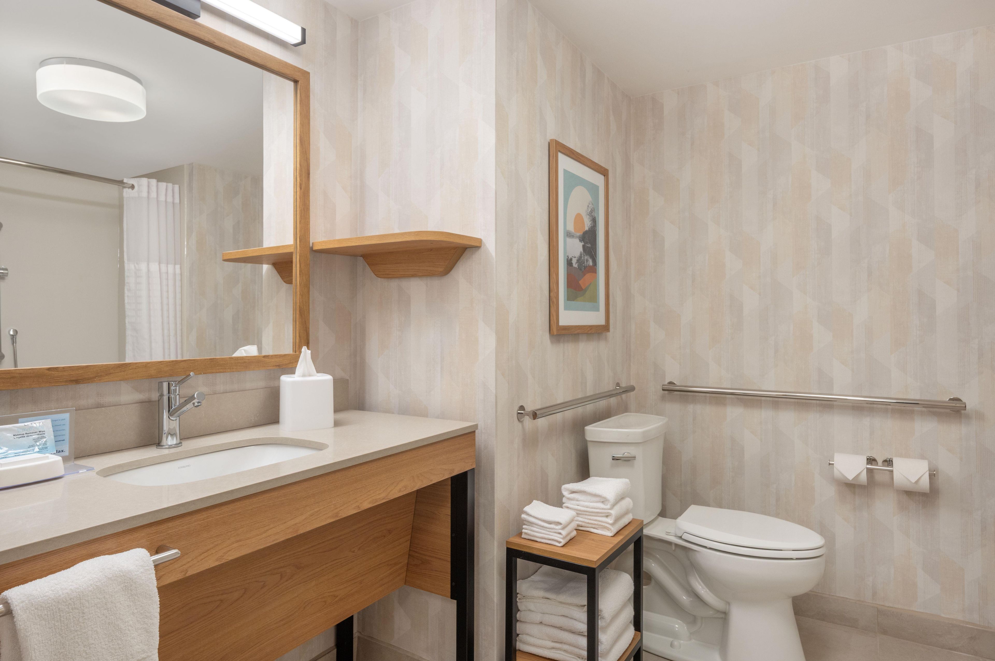 A modern bathroom with a sink, mirror, toilet, and towel rack.