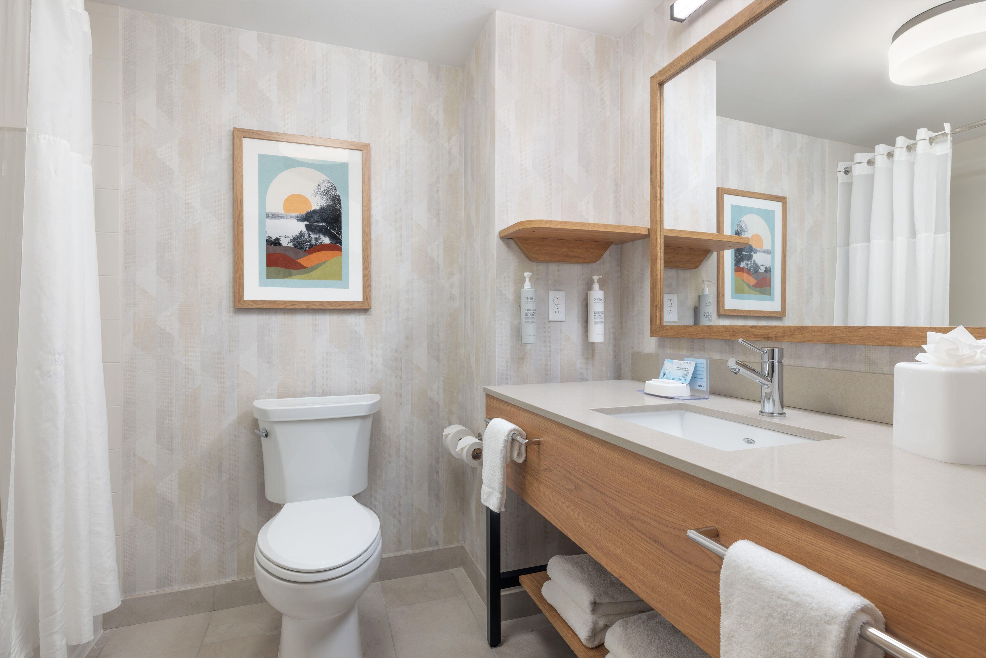 Une salle de bain moderne avec des toilettes, un lavabo et un miroir.