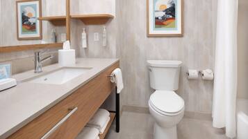 A modern bathroom with a wooden vanity, a toilet, and two framed pictures on the wall.