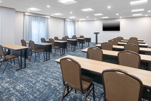 A conference room with multiple tables and chairs, a flat-screen TV mounted on the wall, and a carpeted floor. - Hampton Inn & Suites Berkshires-Lenox (Lenox)
