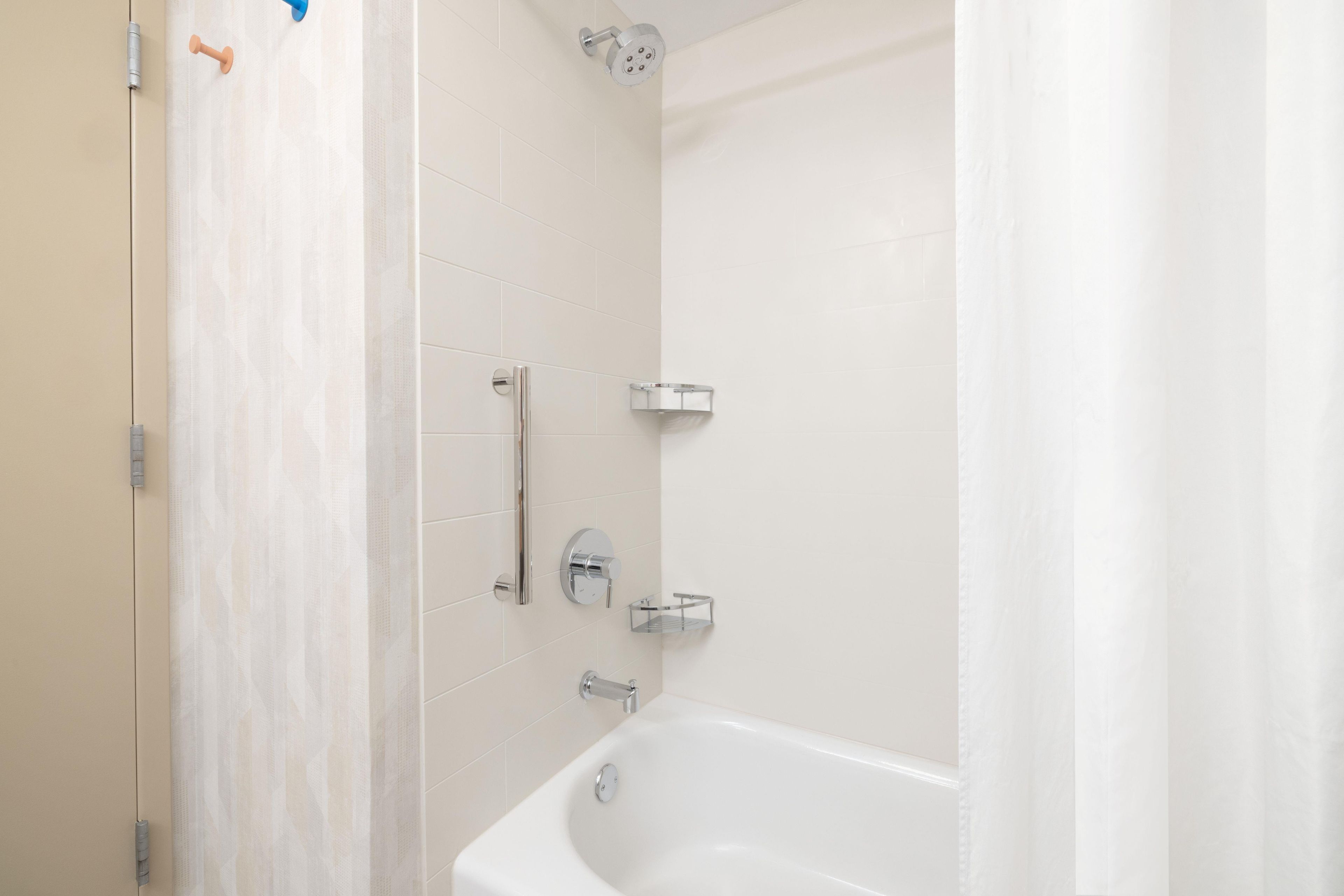 A bathroom with a bathtub, a showerhead, and a towel rack.