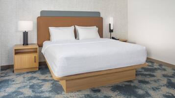 Una habitación de hotel con una cama grande, mesitas de noche de madera, una lámpara y un teléfono.