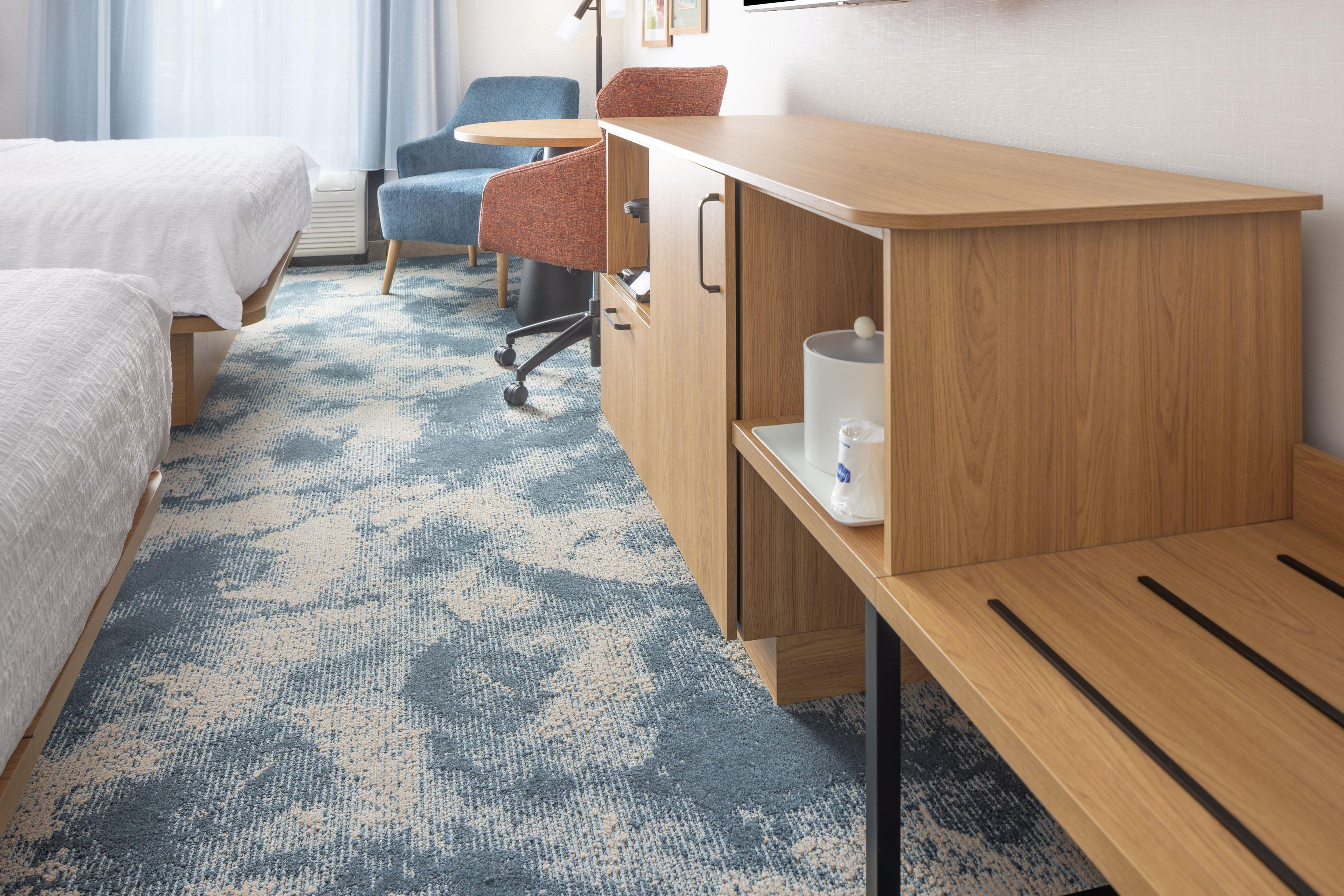 Ein Hotelzimmer mit Bett, Schreibtisch, Stuhl und Teppichboden.