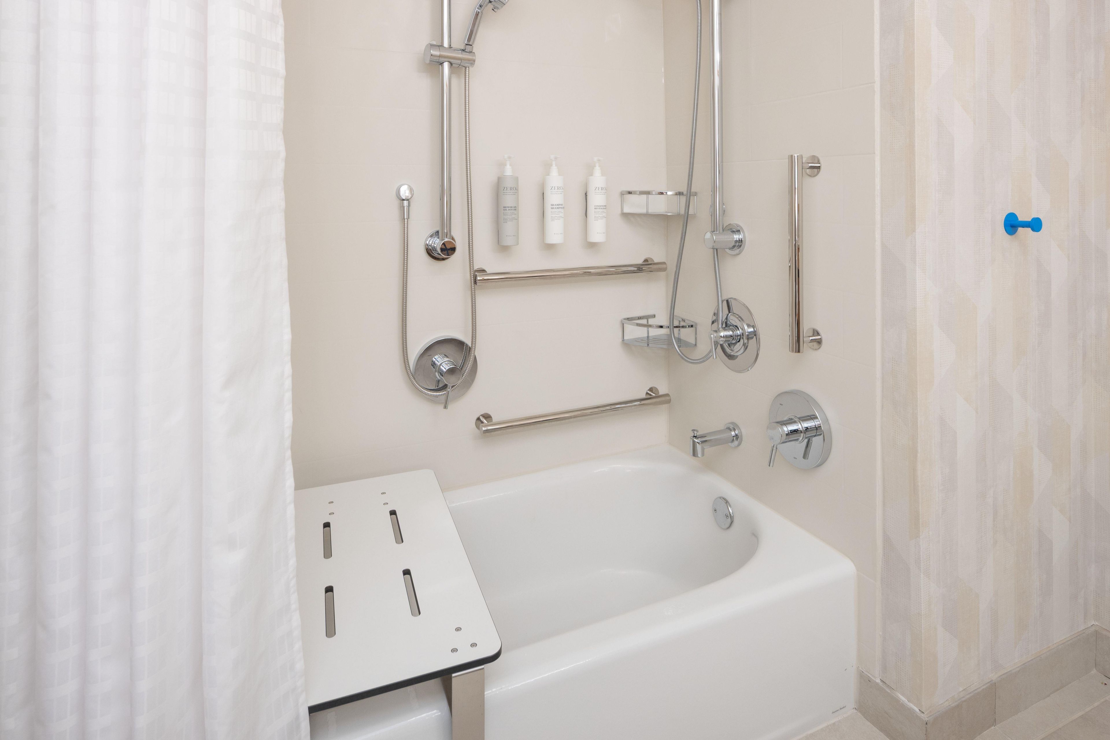 Une salle de bain moderne équipée d’une baignoire, d’une douche et de barres d’appui.