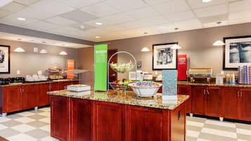 A buffet area with a variety of food items, including fruits and beverages, and a coffee station.