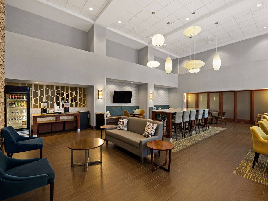 A spacious lobby with a seating area, a bar, and a television screen.